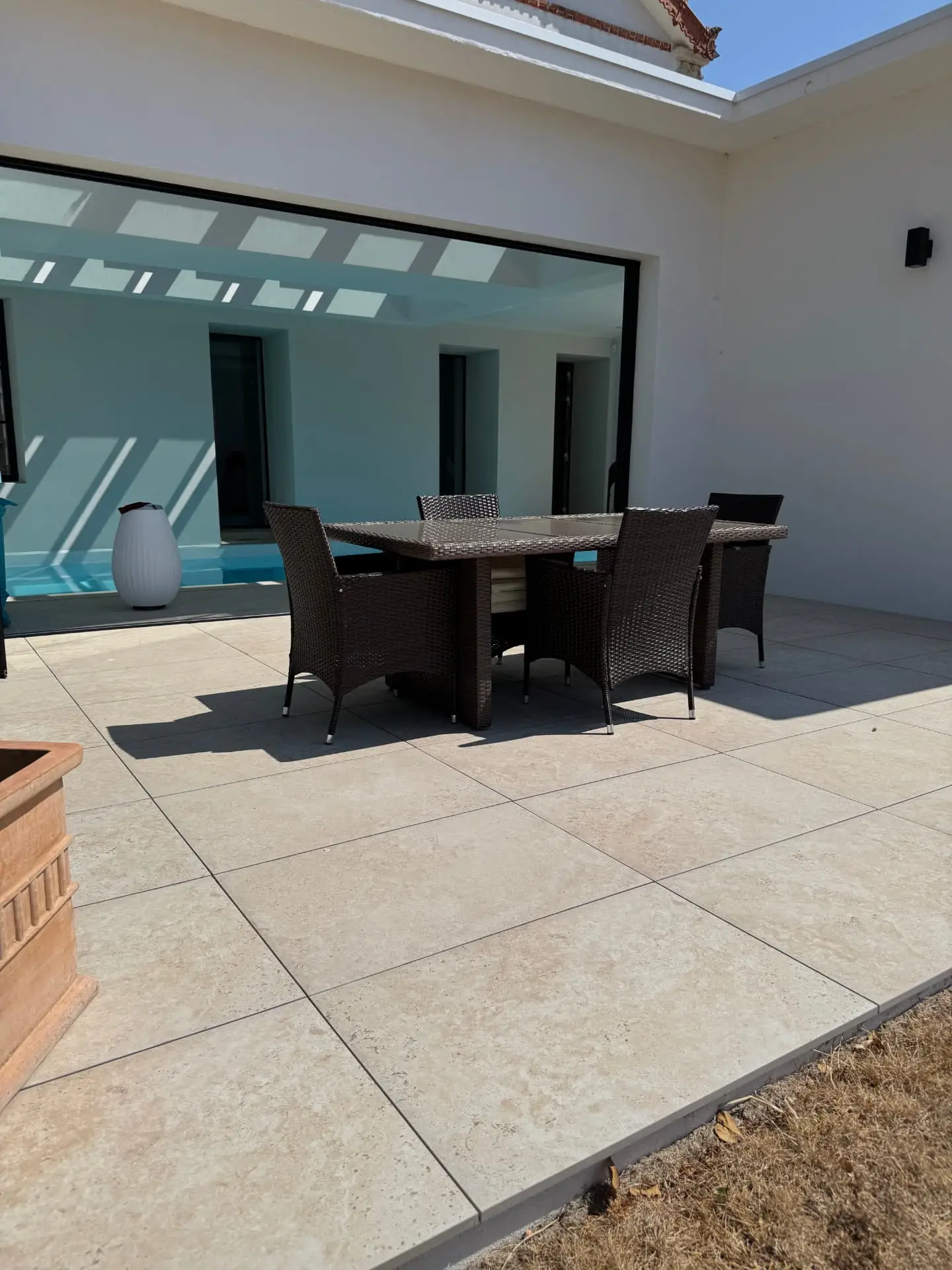 Terrasse en dallage grand format clair au bord d'une piscine